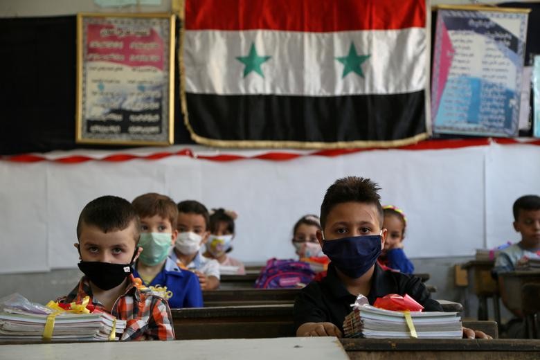 Students wearing protective face masks sit in a classroom as a school year kicks off amid concerns about the spread of the coronavirus, in Damascus, Syria. REUTERS/Yamam Al Shaar    